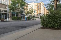 a empty street in the city with buildings and trees lined up on either side of the road