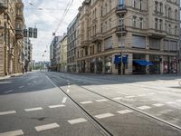 street corner with tracks going through the center with cars on the road and buildings on both sides