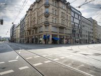street corner with tracks going through the center with cars on the road and buildings on both sides