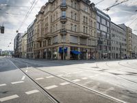 street corner with tracks going through the center with cars on the road and buildings on both sides