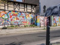 a wall of street graffiti and a street corner with people walking past it and another building in the back ground