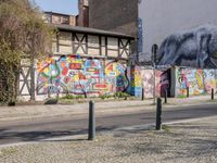 a wall of street graffiti and a street corner with people walking past it and another building in the back ground