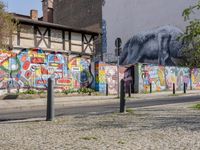 a wall of street graffiti and a street corner with people walking past it and another building in the back ground