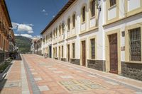 a street with some houses in front of a hill range in ecuador by an electric line