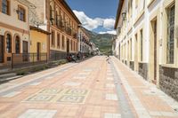 a street with some houses in front of a hill range in ecuador by an electric line