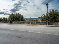 a street with a few cars parked near it on a cloudy day next to a stone wall