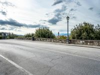 a street with a few cars parked near it on a cloudy day next to a stone wall