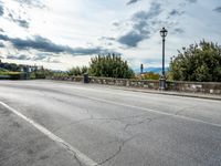 a street with a few cars parked near it on a cloudy day next to a stone wall