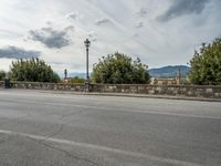 a street with a few cars parked near it on a cloudy day next to a stone wall