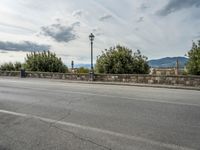 a street with a few cars parked near it on a cloudy day next to a stone wall