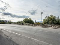 a street with a few cars parked near it on a cloudy day next to a stone wall