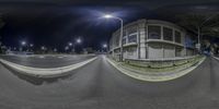 a fish - eye view of a road on a night with street lamps and buildings