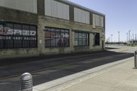 a motorcycle shop along a street with a sign attached to the side wall next to it