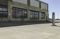 a motorcycle shop along a street with a sign attached to the side wall next to it