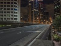 an empty roadway with tall buildings in the distance under a cloudy sky at night, with a sign on it at the end