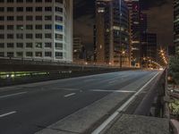 an empty roadway with tall buildings in the distance under a cloudy sky at night, with a sign on it at the end