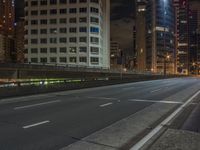 an empty roadway with tall buildings in the distance under a cloudy sky at night, with a sign on it at the end