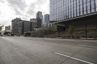a street with an empty road surrounded by high rise building on the other side of the building