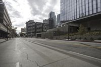 a street with an empty road surrounded by high rise building on the other side of the building