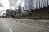 a street with an empty road surrounded by high rise building on the other side of the building