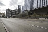 a street with an empty road surrounded by high rise building on the other side of the building