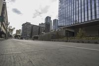 a street with an empty road surrounded by high rise building on the other side of the building