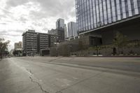 a street with an empty road surrounded by high rise building on the other side of the building