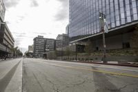 a street with an empty road surrounded by high rise building on the other side of the building