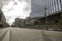 a street with an empty road surrounded by high rise building on the other side of the building