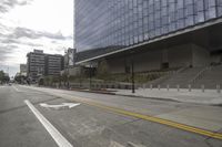 a street with an empty road surrounded by high rise building on the other side of the building