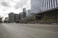 a street with an empty road surrounded by high rise building on the other side of the building