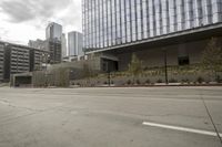 a street with an empty road surrounded by high rise building on the other side of the building