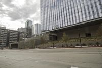 a street with an empty road surrounded by high rise building on the other side of the building