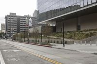a street with an empty road surrounded by high rise building on the other side of the building