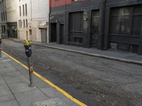 an empty street that has a parking meter on it near some buildings in front of the building
