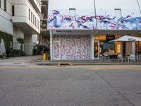 an outside view of a building with graffiti paint on it's side, and street furniture set up around the corner