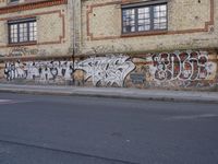 an image of a street scene with two motorcycles and some graffiti on the wall near the street