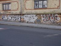 an image of a street scene with two motorcycles and some graffiti on the wall near the street