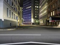 street scene at night with tall buildings and traffic lights on the corner of a street