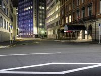 street scene at night with tall buildings and traffic lights on the corner of a street