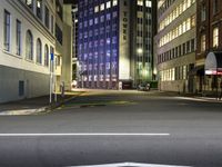 street scene at night with tall buildings and traffic lights on the corner of a street