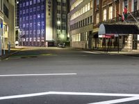 street scene at night with tall buildings and traffic lights on the corner of a street