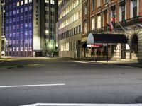 street scene at night with tall buildings and traffic lights on the corner of a street