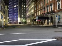 street scene at night with tall buildings and traffic lights on the corner of a street