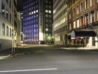 street scene at night with tall buildings and traffic lights on the corner of a street