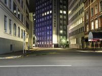 street scene at night with tall buildings and traffic lights on the corner of a street