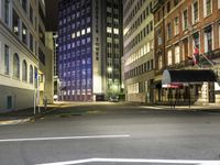 street scene at night with tall buildings and traffic lights on the corner of a street