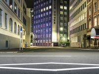 street scene at night with tall buildings and traffic lights on the corner of a street