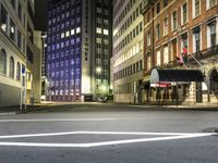 street scene at night with tall buildings and traffic lights on the corner of a street