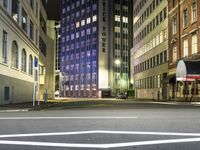 street scene at night with tall buildings and traffic lights on the corner of a street